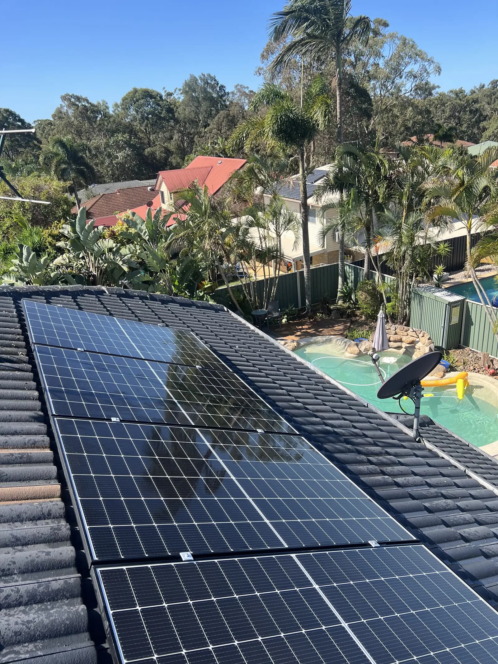 A long run of solar panels on a tiled roof in a Brisbane suburb