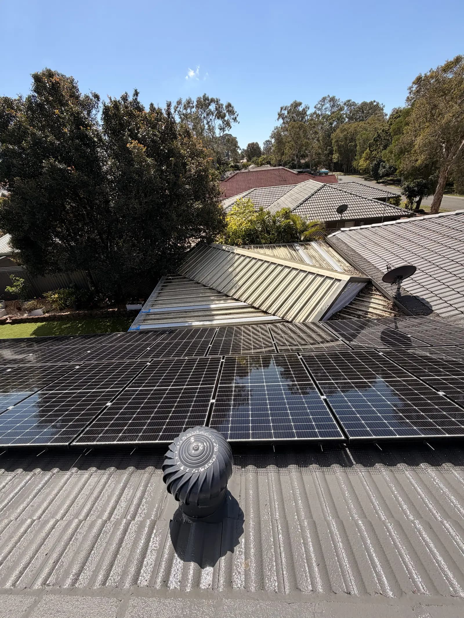 Solar array on a tiled roof next to a whirlybird roof vent